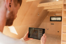 Man Using Tablet Pc To Visualise Home Interior At New Wooden Eco House