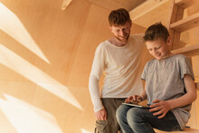Father And Son Using Tablet Pc For Modeling Home Interior In Eco Wooden House