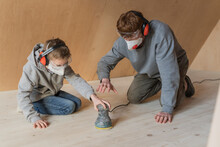Father And Son Sanding The Floor In Their New Eco House