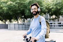 Smiling Man Wearing Wireless Headphones Standing With Bicycle