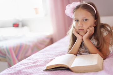 Wall Mural - a girl of eight years reads a book