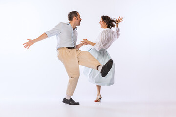 Wall Mural - Portrait of young stylish couple, man and woman, dancing isolated over white studio background. Classic dance styles