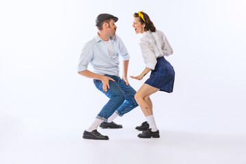 Canvas Print - Portrait of young emotive couple, man and woman, dancing retro dance isolated over white background. Funny faces