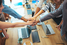 Shot Of A Group Of Businesspeople High Fiving While Sitting In A Meeting. Teambuilding Concept. Business Team Putting Their Hands Together. Stack Of Hands. Unity And Teamwork Concept.