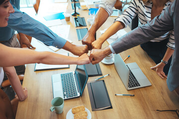 Happy motivated young and older generation multiracial business people joining fists, showing support and team spirit together, celebrating corporate achievement or success at meeting in office.