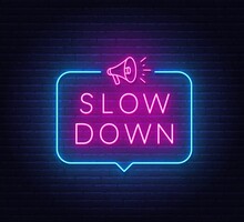Slow Down Neon Sign In The Speech Bubble On Brick Wall Background.