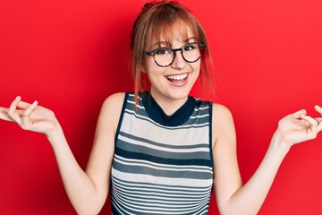 Canvas Print - Redhead young woman wearing casual clothes and glasses celebrating victory with happy smile and winner expression with raised hands