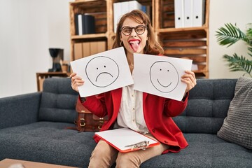 Canvas Print - Young beautiful woman working on depression holding sad to happy emotion paper sticking tongue out happy with funny expression.