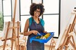 © Krakenimages.com - Young african american woman smiling confident drawing using roller at art studio