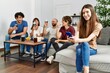 © Krakenimages.com - Group of young friends having party sitting on the sofa at home. Woman smiling happy using smartphone at home.