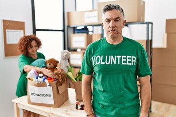 Canvas Print - Middle age man wearing volunteer t shirt at donations stand skeptic and nervous, frowning upset because of problem. negative person.