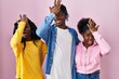 Group of three young black people standing together over pink background surprised with hand on head for mistake, remember error. forgot, bad memory concept.