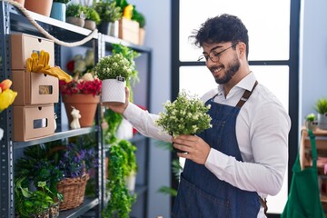 Poster - Young hispanic man florist smiling confident holding plants at florist shop