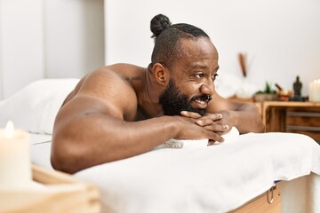 Sticker - Young african american man smiling confident lying on massage table at beauty center