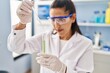 © Krakenimages.com - Young hispanic woman wearing scientist uniform using pipette working at laboratory