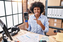 Black Woman With Curly Hair Working At Small Business Ecommerce Holding Credit Card And Dataphone Smiling Happy Pointing With Hand And Finger