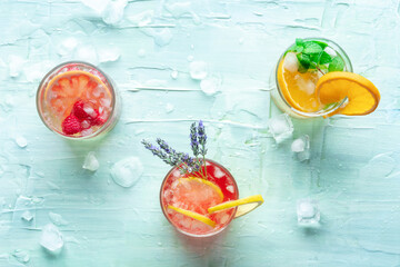 Poster - Fresh summer cocktails or mocktails, cold drinks with citrus fruits and lavender, party lemonade, overhead flat lay shot on a blue background with ice