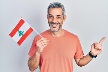 Sticker - Handsome middle age man with grey hair holding lebanon flag smiling happy pointing with hand and finger to the side