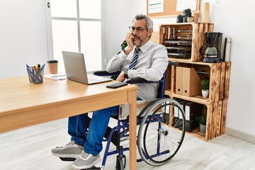 Sticker - Middle age hispanic man working at the office sitting on wheelchair looking stressed and nervous with hands on mouth biting nails. anxiety problem.