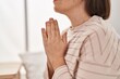 © Krakenimages.com - Middle age woman praying sitting on bed at bedroom