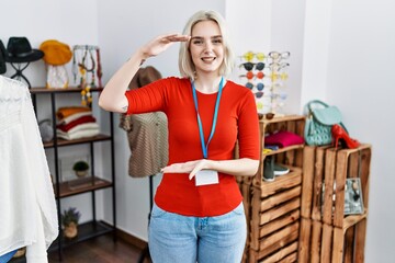 Poster - Young caucasian woman working as manager at retail boutique gesturing with hands showing big and large size sign, measure symbol. smiling looking at the camera. measuring concept.