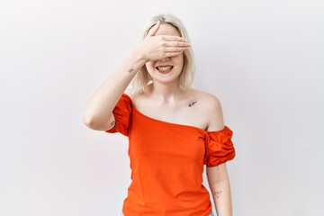 Poster - Young caucasian woman standing over isolated background smiling and laughing with hand on face covering eyes for surprise. blind concept.