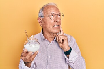 Canvas Print - Senior man with grey hair holding bowl with sugar serious face thinking about question with hand on chin, thoughtful about confusing idea