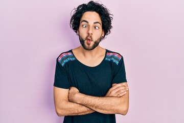 Poster - Handsome hispanic man with arms crossed gesture making fish face with mouth and squinting eyes, crazy and comical.