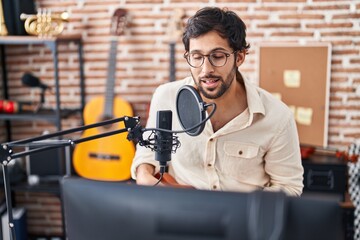 Wall Mural - Young hispanic man musician singing song playing ukulele at music studio