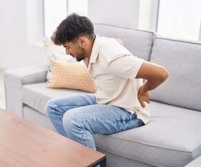 Sticker - Young arab man suffering for backache sitting on sofa at home