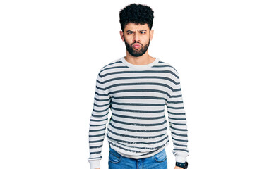 Sticker - Young arab man with beard wearing casual striped sweater making fish face with lips, crazy and comical gesture. funny expression.