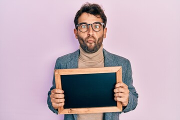 Sticker - Handsome man with beard holding blackboard making fish face with mouth and squinting eyes, crazy and comical.