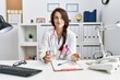 © Krakenimages.com - Young doctor woman holding glass of water and prescription pills smiling looking to the side and staring away thinking.