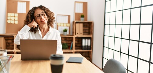 Sticker - Middle age hispanic woman working at the office wearing glasses smiling doing phone gesture with hand and fingers like talking on the telephone. communicating concepts.