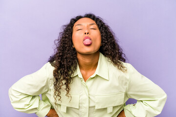 Wall Mural - Young hispanic woman isolated on purple background funny and friendly sticking out tongue.