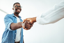 Young Business Couple Handshaking In The Office In Front Of Their Team. Recruiter Shaking Successful Smiling Businesswoman Candidate Hand At Meeting, Congratulating With Getting New Job