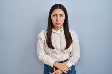 Poster - Young latin woman standing over blue background depressed and worry for distress, crying angry and afraid. sad expression.