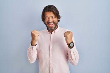 Canvas Print - Handsome middle age man wearing elegant shirt background very happy and excited doing winner gesture with arms raised, smiling and screaming for success. celebration concept.