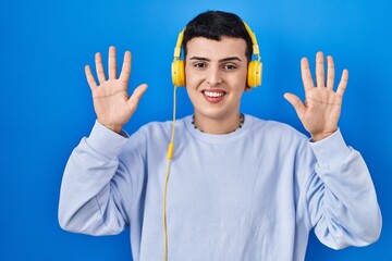 Sticker - Non binary person listening to music using headphones showing and pointing up with fingers number ten while smiling confident and happy.