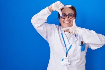 Sticker - Senior woman with glasses wearing scientist uniform smiling making frame with hands and fingers with happy face. creativity and photography concept.