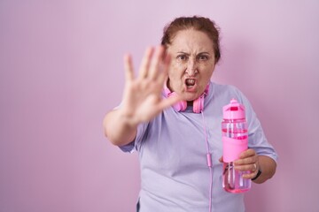 Sticker - Senior woman wearing sportswear and headphones doing stop gesture with hands palms, angry and frustration expression