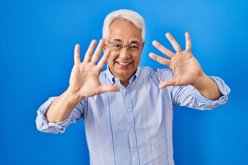 Canvas Print - Hispanic senior man wearing glasses showing and pointing up with fingers number ten while smiling confident and happy.