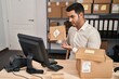 © Krakenimages.com - Young hispanic man e-commerce business worker having video call showing package at office
