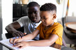 © Wavebreak Media - Image of african american father and son reading braille