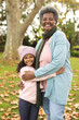 © wavebreak3 - Vertical image of happy african american grandmother and granddaughter embracing in garden