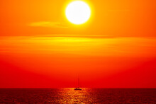 Silhouette Of A Sailing Boat In Sunset Sunrise Time And Ocean Horizon.