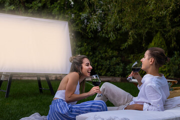 In love young couple laughing and having fun while drinking red wine and watching a movie as a date