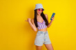 © deagreez - Photo of impressed cute girl dressed swimsuit bra cap writing modern gadget thumb empty space isolated yellow color background