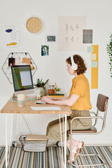 Aufkleber - Youthful creative girl in casualwear and headphones sitting in front of computer screen and working over creation of new website