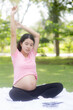 © NT_studio - Happiness young asian woman pregnant sitting doing sport exercise with stretch hands muscle for health care at park, mother practicing yoga for leisure in the garden, activity for pregnancy concept.